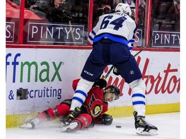 Ottawa Senators right wing Evgenii Dadonov (63) gets checked heavily by Winnipeg Jets defenceman Logan Stanley.