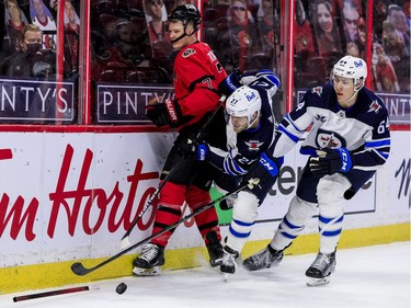 Ottawa Senators left wing Brady Tkachuk (7) breaks his stick as he is checked into the end boards by Winnipeg Jets left wing Nikolaj Ehlers (27) and defenceman Logan Stanley.