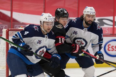Winnipeg Jets defenceman Neal Pionk (4) and centre Nate Thompson defend against Ottawa Senators rookie Tim Stuetzle on Monday night at the Canadian Tire Centre.