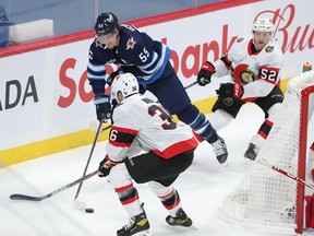 Mark Scheifele #55 of the Winnipeg Jets moves the puck under pressure from Colin White #36 and Olle Alsing #52 of the Ottawa Senators during first period NHL action on Saturday at Bell MTS Place in Winnipeg, Manitoba, Canada.
