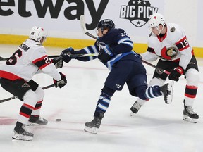 Senators winger Drake Batherson, right, helps defenceman Erik Brannstrom pressure Jets forward Mason Appleton during the first period of Saturday's game in Winnipeg.