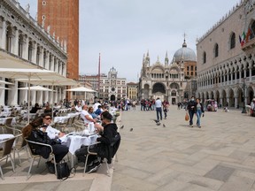 People sit at outdoor tables at St. Mark's Square as Italy lifts quarantine restrictions for travellers arriving from European Union countries, Britain and Israel and begins offering COVID-free flights in a bid to revive the tourism industry, in Venice, Italy, May 16, 2021.