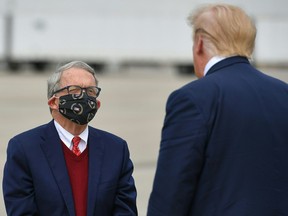 U.S. President Donald Trump speaks with Ohio Governor Mike DeWine upon arrival at Rickenbacker International Airport in Columbus, Ohio on Oct. 24, 2020.
