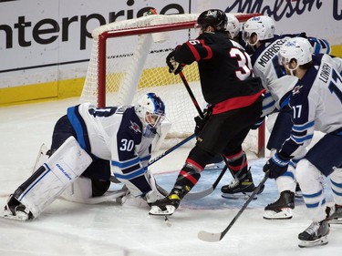 Winnipeg Jets goalie Laurent Brossoit (30) makes a save in front of Ottawa Senators centre Colin White (36) in the third period at the Canadian Tire Centre.