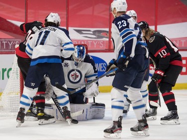 Winnipeg Jets goalie Laurent Brossoit (30) makes a save in front of Ottawa Senators centre Colin White (36) in the second period at the Canadian Tire Centre on Monday.