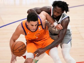 Clippers guard Patrick Beverley (right) tries to steal the ball away from Suns guard Devin Booker (left) during Game 4 of the NBA's Western Conference Finals at Staples Center in Los Angeles, Saturday, June 26, 2021.