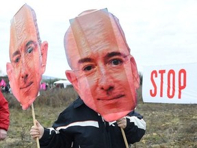 An activist of the Attac association holds a cutout sign depicting Amazon CEO Jeff Bezos, in front of a banner reading "Stop Amazon", during a demonstration on the site where Amazon plans to build a 38.800 square metres warehouse, in Fournes, southeastern France on January 30, 2021. (Photo by Sylvain THOMAS / AFP) (Photo by SYLVAIN THOMAS/AFP via Getty Images)