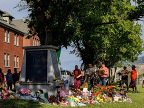 Charles Goforth of Peepeekisis Cree Nation of Saskatchewan, right, is joined by Cherokee Eagletail and Ansen Eagletail of Tsuut'ina Nation of Alberta as they drum and sing at the former Kamloops Indian Residential School to honour the 215 children whose remains have been discovered buried near the facility, in Kamloops, B.C., on June 3, 2021.