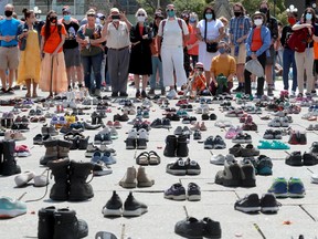 Standing behind the hundreds of shoes that represented the original 215 children found buried at a residential school, people listen to the speakers on Parliament Hill before the march. Hundreds joined MPs Charlie Angus, Mumilaaq Qaqqaq and Indigenous elders for a march to demand an independent investigation into the mounting residential school children deaths.