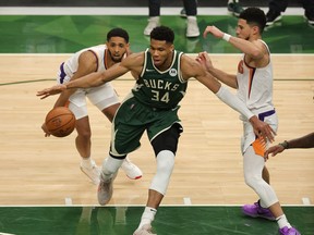 Giannis Antetokounmpo of the Milwaukee Bucks drives into the lane as Devin Booker of the Phoenix Suns defends during the second half in Game 3 of the NBA Finals at Fiserv Forum on July 11, 2021.