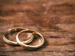 A pair of golden wedding rings on wooden background.