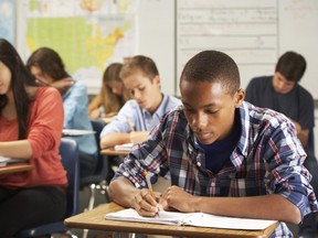 Male student in classroom writing in notebook