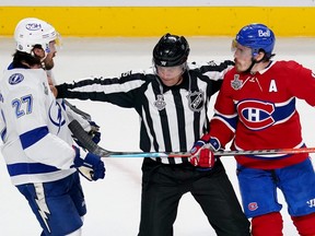 Brendan Gallagher of the Montreal Canadiens and Ryan McDonagh of the Tampa Bay Lightning are broken apart by linesman Jonny Murray during the second period in Game Four of the 2021 NHL Stanley Cup Final at the Bell Centre on July 5, 2021 in Montreal.