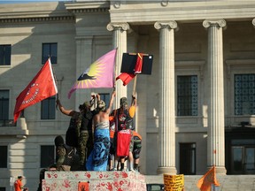 Protesters stand on a pedestal that once supported a statue of Queen Victoria, toppled during a rally outside the provincial legislature on Canada Day in Winnipeg.