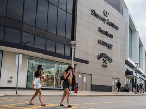 Two women carrying shopping bags cross the street in front of Sherway Gardens during the stage two reopening from coronavirus disease (COVID-19) restrictions in Toronto, Ontario, Canada June 30, 2021.