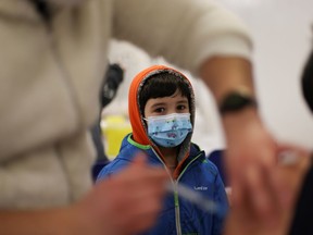 A child looks on as a woman receives a dose of Pfizer/BioNTech coronavirus disease (COVID-19) vaccine during a vaccination campaign inside the University of Santiago, Chile June 30, 2021. REUTERS/Ivan Alvarado ORG XMIT: GGGIA105