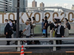 People stand in front of Tokyo 2020 Olympic Games signage as the COVID-19 outbreak continues in Tokyo, Japan, July 21, 2021.