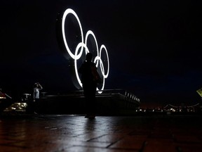 Visitors take a photo in front of a newly installed Olympic rings for celebrating the 2020 Tokyo Olympic Games in Yokohama, Japan, June 30, 2021.