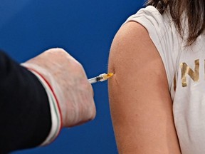 A medical worker (left) injects a woman with a dose of the AstraZeneca/Oxford vaccine on March 24, 2021 at a vaccination hub outside Rome's Termini railway station.