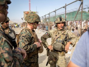 U.S. Marine Brigadier General Farrell J. Sullivan, the commander of the Naval Amphibious Task Force 51/5th Marine Expeditionary Brigade, speaks to a service member of the Italian coalition force during an evacuation at Hamid Karzai International Airport in Kabul, Aug. 24, 2021.