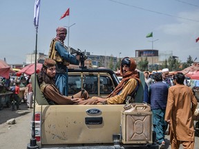 Taliban fighters on a pickup truck move around a market area, flocked with local Afghan people at the Kote Sangi area of Kabul on August 17, 2021.