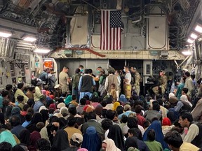 A newborn baby is looked after prior taking off with other Afghan evacuees on a C-17 Globemaster III at a Middle East staging area on Aug. 23, 2021.