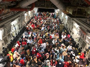 Evacuees termed Canadian Entitled Persons sit in a Royal Canadian Air Force (RCAF) C-177 Globemaster III transport plane for their flight to Canada from Kabul, Afghanistan, on Aug. 23, 2021.