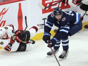 Ottawa Senators forward Shane Pinto clears the puck from his backside with Winnipeg Jets forward Jansen Harkins closing in on Sunday.