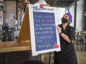 Kitchen manager Fernanda Tavares provides patrons notice about vaccine passports at Firkin on the Bay pub in the Humber Bay Shores neighbourhood on Sept. 21, 2021.