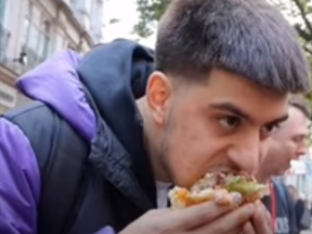TikTok user Jordan Adams trolls vegan protesters by eating giant burger during demonstration.