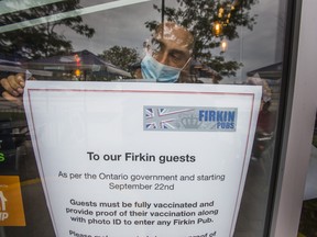 Host Jason Singh with a notice of Ontario's new vaccination requirement at Firkin on the Bay pub in the Humber Bay Shores neighbourhood in Toronto on Tuesday September 21, 2021.