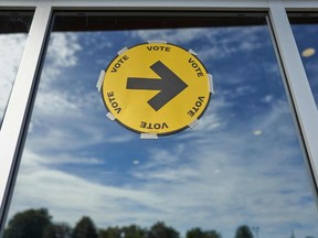 A sign points the way to a polling station for voting in the 2021 Canadian election in Oshawa, Ontario on September 20, 2021. - Voters lined up to cast ballots in Canadian elections that are headed for a photo finish, with liberal Prime Minister Justin Trudeau's bid for a third term threatened by rookie conservative leader Erin O'Toole's strong challenge. (Photo by Geoff Robins / AFP)