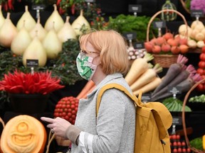 FILE: A woman wearing a face mask walks by a display.