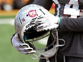 Gees-Gees receiver Daniel Oladejo rubs the No. 99 sticker placed on his helmet to honour Francis Perron during Saturday's pre-game ceremony in Kingston.