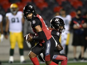 Redblacks quarterback Caleb Evans holds the ball after faking a handoff to running back Timothy Flanders (20) during the first half of Tuesday's game against the Elks.