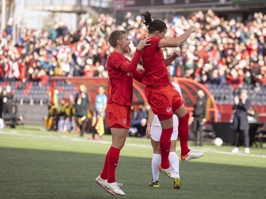 Canada's Christine Sinclair, right, celebrates with teammates after scoring against New Zealand's goalkeeper, Erin Nayler, in the first half.