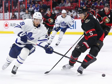 Michael Bunting #58 of the Toronto Maple Leafs plays the puck past Nick Holden #5 of the Ottawa Senators.