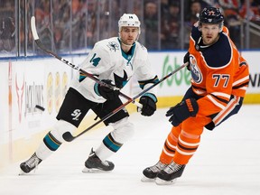 Edmonton Oilers' Oscar Klefbom (77) and San Jose Sharks' Dylan Gambrell (14) watch a flying puck during the second period of a NHL game at Rogers Place in Edmonton, on Saturday, Feb. 9, 2019.