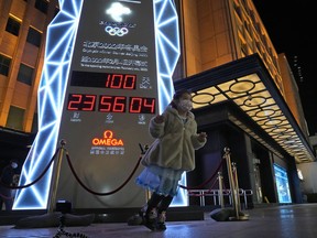 A young child stands near the countdown clock of the 2022 Beijing Winter Olympics as it crosses into the 100 days countdown to the opening of the Winter Olympics in Beijing, China, Tuesday, Oct. 26, 2021.