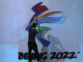 A man adjusts an emblem of the Beijing 2022 Winter Olympic Games before a ceremony unveiling the slogan, in Beijing, China September 17, 2021.