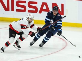 Ottawa Senators defenceman Erik Brannstrom (left) battles Winnipeg Jets forward Andrew Copp for the puck during a pre-season game on Sept. 26, 2021.
