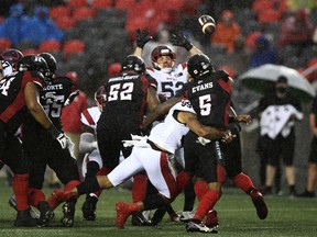 Ottawa Redblacks quarterback Caleb Evans (5) throws the ball as he gets tackled by Montreal Alouettes defensive lineman Jamal Davis II (99) during first half CFL football action in Ottawa on Saturday, Oct. 16, 2021.
