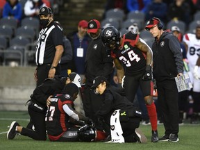 Redblacks head coach Paul LaPolice, far right, and others look on as returned DeVonte Dedmon receives medical attention for a leg injury late in the first half of Saturday's game against the Alouettes.