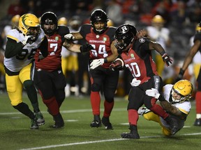 Redblacks running back Timothy Flanders (20) tries to run past the tackle of Elks defensive lineman Thomas Costigan last Tuesday's game at TD Place stadium.