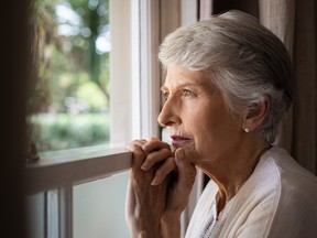 A woman looks out a window at a long-term care home.