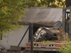 Destroyed home with car on its side beside it.