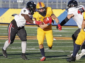 Gaels running back Burke Derbyshire, 3, avoids a tackle from Ravens linebacker Darren Kyeremeh during Saturday's OUA football playoff game at Kingston.