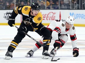 Mike Reilly of the Boston Bruins and Tim Stuetzle of the Ottawa Senators battle for control of the puck during the first period at TD Garden on Nov. 09, 2021 in Boston.