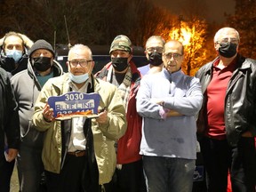 Abdulhamid Hussein (holding the taxi sign) and more than 100 Ottawa cabbies who have not returned to driving since the pandemic began say they have been stymied by not just COVID-19, but also by their former company, their union and the insurance industry.