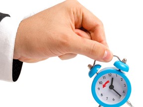 A businessman is holding an alarm clock. Transition to winter time, transfer of hours to an hour back. Watch in hand. The concept of hourly pay, time. Late for work. Full or incomplete rate. Overtime
